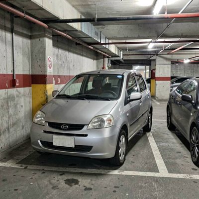 a small city car in a tight parking space, no license plate