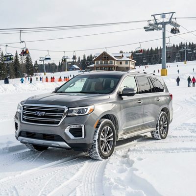 a large SUV at a ski resort in snow, no license plate