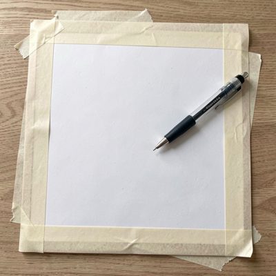 a drawing board with masking tape and a technical pen