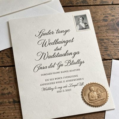 a wedding invitation with calligraphy and a stamp