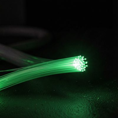 a fibre optic cable end glowing green in a dark room