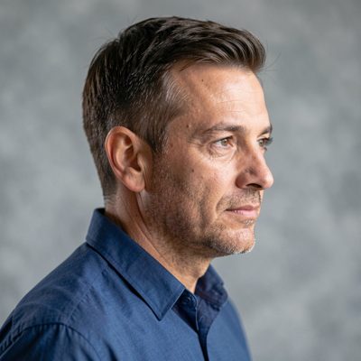 a profile portrait of an adult man against a soft grey background