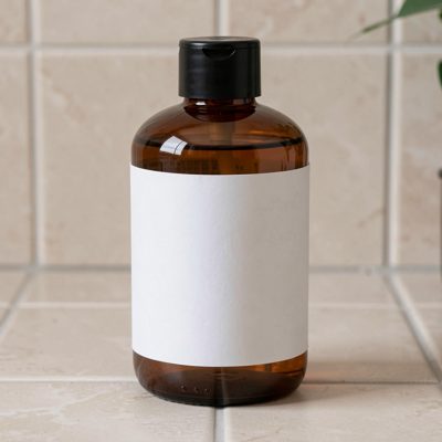 a shampoo bottle with a blank unprinted white label on a tiled surface