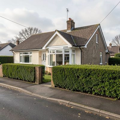 a bungalow with a bay window and neat hedge