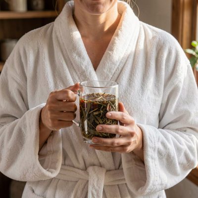 a client in a robe holding a herbal tea