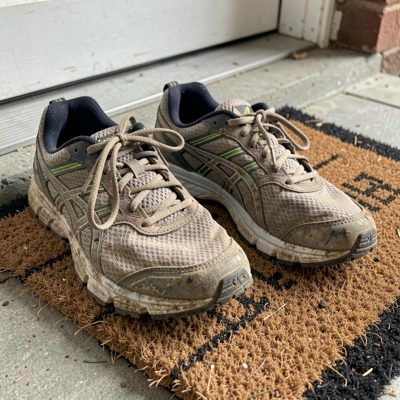 a pair of worn running trainers on a doormat
