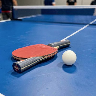 a table tennis bat and ball on a blue table
