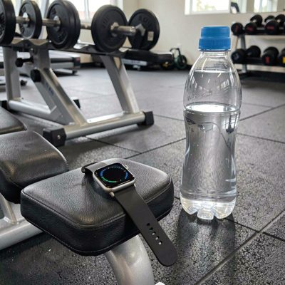 a smartwatch on a gym bench beside a water bottle