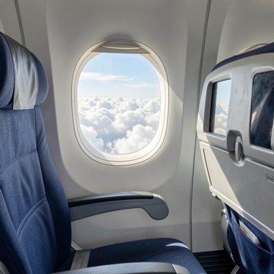an airline seat with a window view of clouds